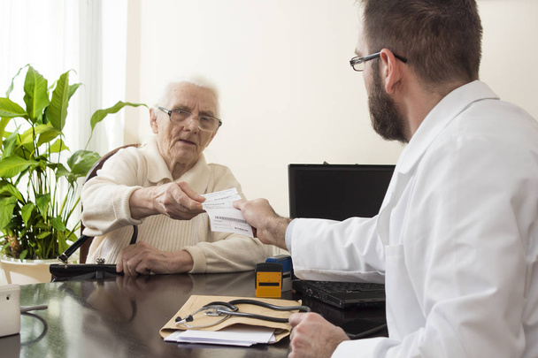 Γηρίατρος γιατρός με έναν ασθενή στο γραφείο του. Ηλικιωμένη γυναίκα στο ο γιατρός Γηρίατρος. - Φωτογραφία, εικόνα