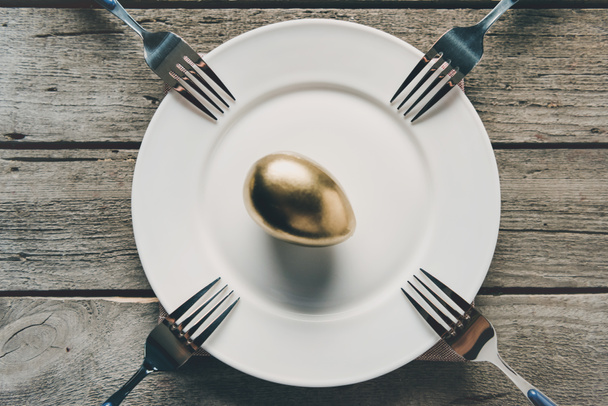 Золотое пасхальное яйцо на тарелке
  - Фото, изображение
