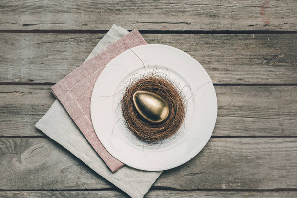 Huevo de Pascua dorado en plato
  - Foto, Imagen