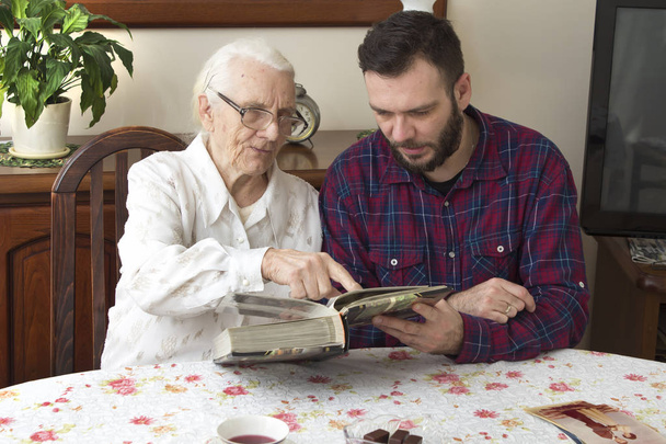 Grand-mère avec petit-fils se rappeler le bon vieux temps regarder album photo
.  - Photo, image