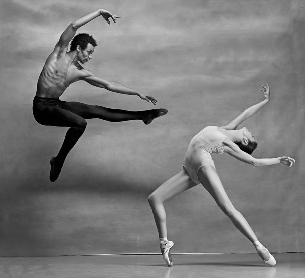 Couple of ballet dancers posing over gray background - Photo, image