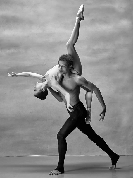 Couple of ballet dancers posing over gray background - Foto, Imagem