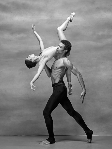 Couple of ballet dancers posing over gray background - Фото, изображение
