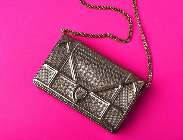 small womans metallized silver bag with metallic chain on pink - 写真・画像