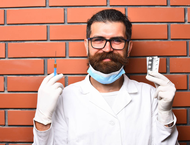 Bearded brutal caucasian doctor or postgraduate student holding pills - Fotografie, Obrázek