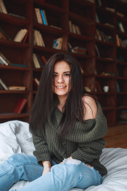 Beautiful girl with dark hair sitting on the bed in the morning - Fotó, kép
