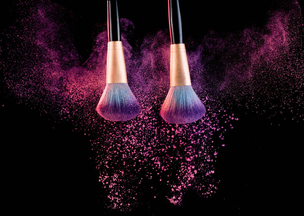 Cosmetics brush with powder explosion on black - Фото, изображение