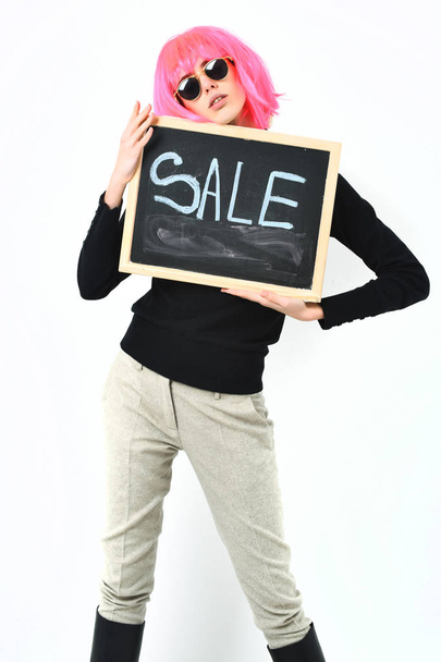 fashionable girl in wig holding board with sale inscription - Zdjęcie, obraz