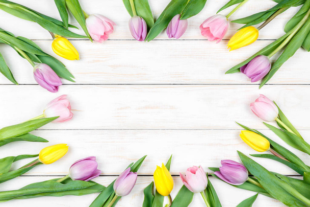 Pink and yellow tulips lying on a white wooden background - Foto, imagen