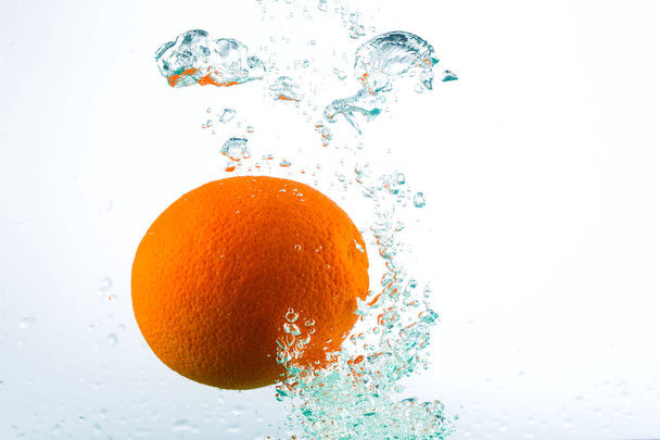 Orange in streams of water on a white background - Foto, Imagen