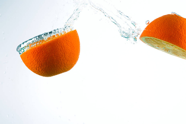 Orange in streams of water on a white background - Zdjęcie, obraz