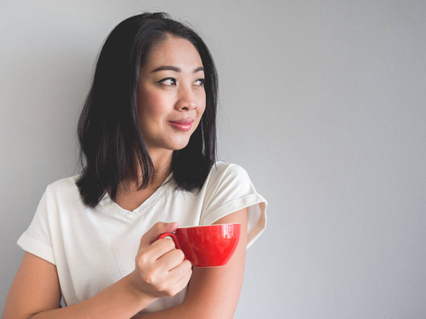 Mosoly ázsiai nő piros pohár kávét iszik. - Fotó, kép