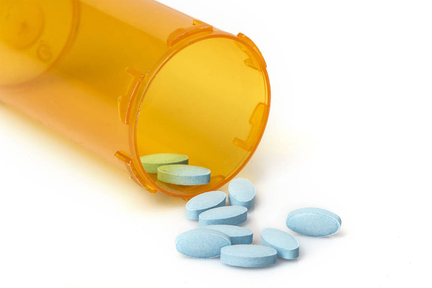 Маленькі сині таблетки, що виливаються з контейнера рецептів
 - Фото, зображення