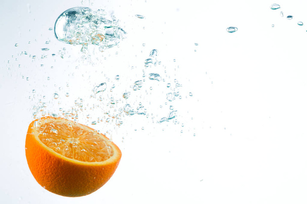 Orange in streams of water on a white background - Foto, afbeelding