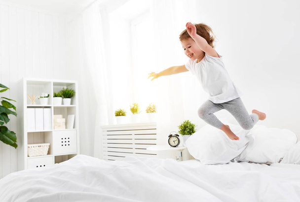 happy child girl  jumps and plays bed - Foto, afbeelding