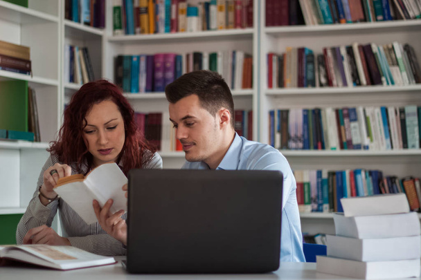 Handsome guy and beautiful redhead girl studying in the library  - Foto, Bild