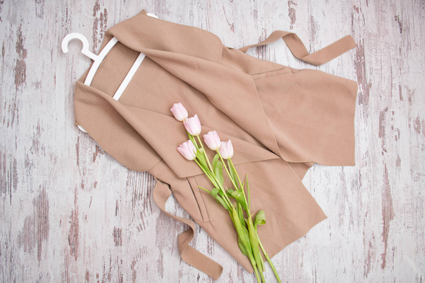 Beige jas met een riem, roze tulpen, witte trempel. Modieuze concept. Van bovenaf bekijken - Foto, afbeelding