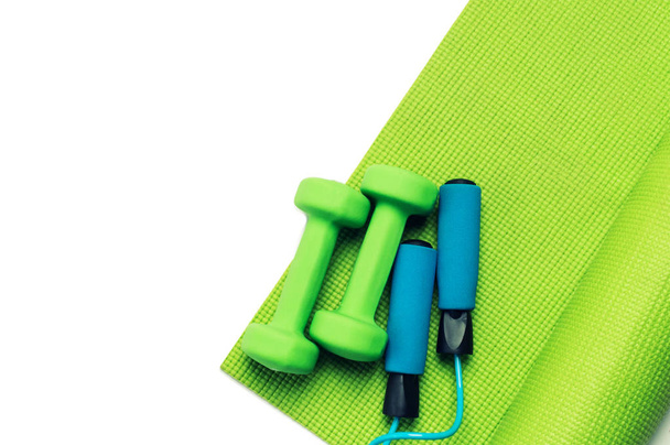 Fitness concept - green yoga mat, dumbbells and skipping rope - Photo, Image