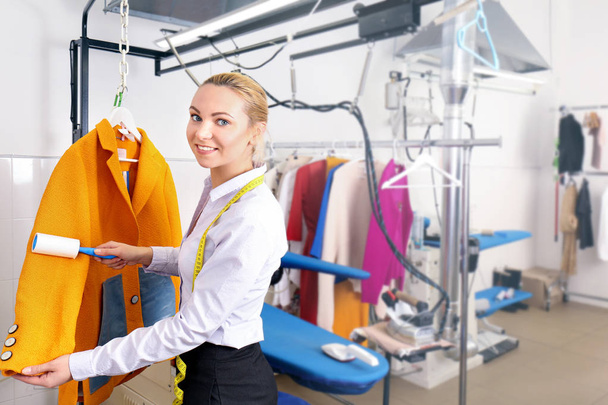Dry cleaning business concept. Woman working with coat and adhesive roller - Valokuva, kuva