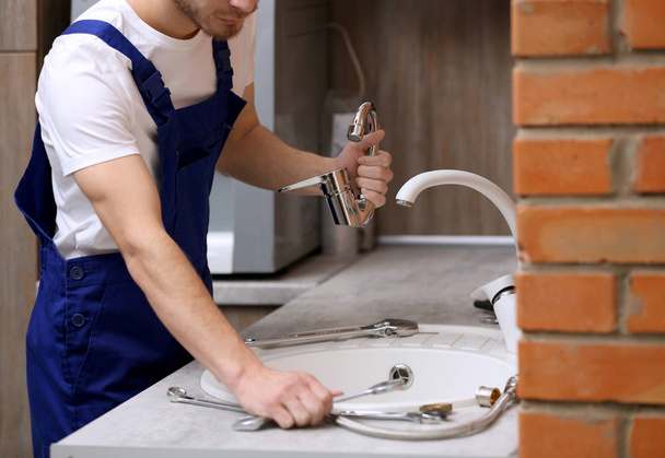 Handsome plumber in kitchen - Foto, Imagen