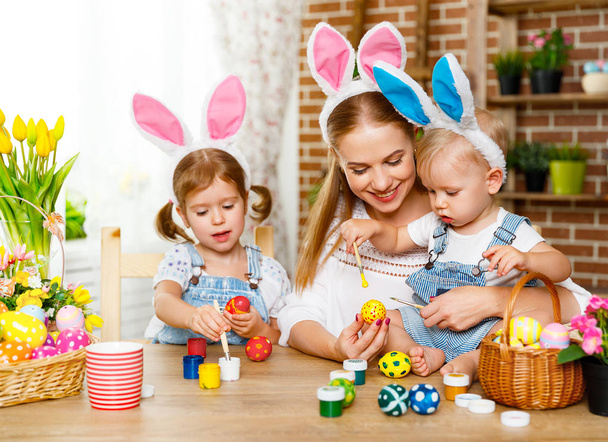 Frohe Ostern! Familienmutter und Kinder bemalen Eier für den Urlaub  - Foto, Bild