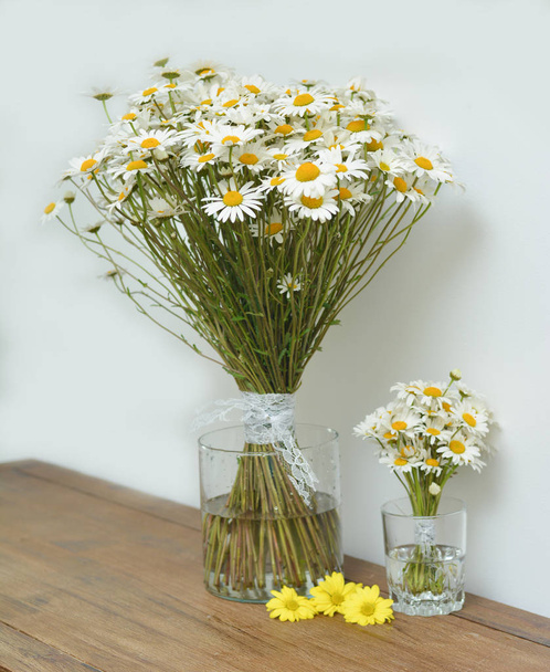 Two bouquets of chamomiles in a glass vase on a table - Foto, Imagen