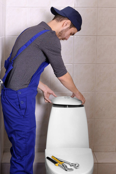 Plumber repairing toilet cistern at water closet - Foto, Imagen