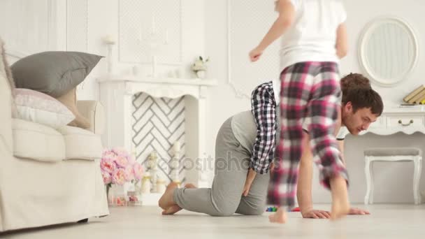 Young father playing with his daughter and son on the living room floor - Filmati, video