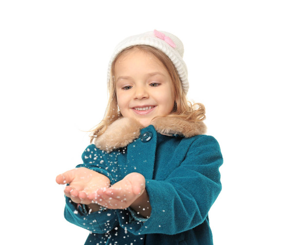 Cute little girl in warm clothes playing with snow on white background - Fotó, kép