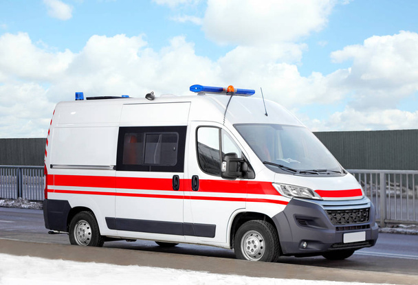 Modern ambulance car on road near construction site - Фото, изображение