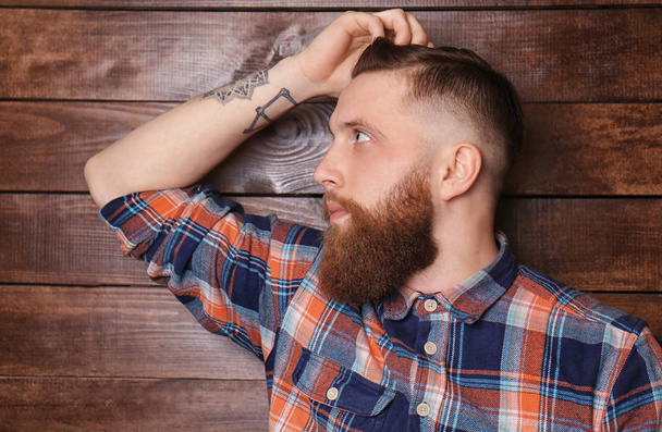 Bearded man posing on wooden background - Foto, afbeelding