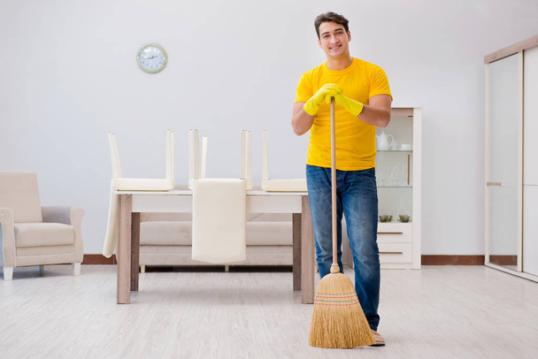 Ο άντρας καθαρίζει το σπίτι βοηθώντας τη γυναίκα του. - Φωτογραφία, εικόνα