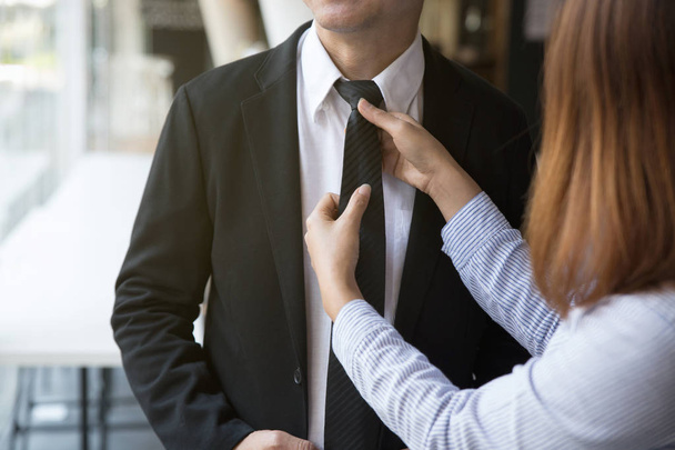 woman arranges necktie knot of man in a suit - Фото, изображение