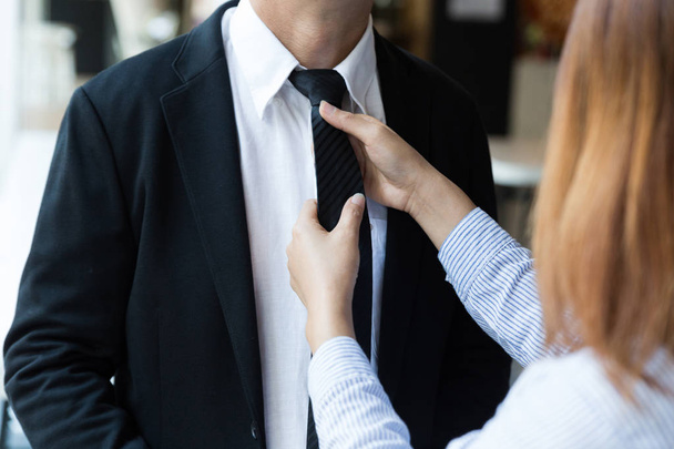 woman arranges necktie knot of man in a suit - Фото, зображення