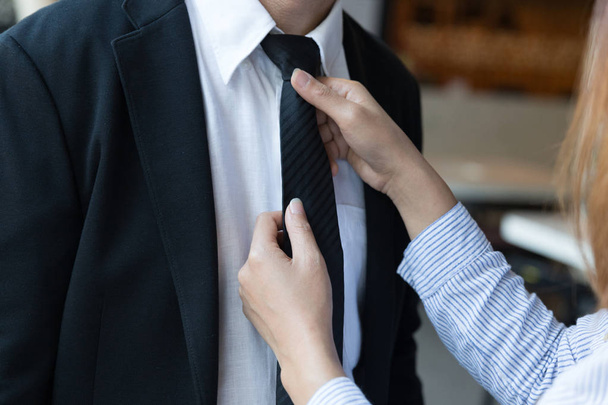 woman arranges necktie knot of man in a suit - Φωτογραφία, εικόνα