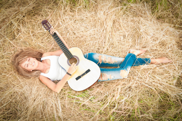 glückliches Mädchen mit Gitarre auf Wiese liegend. - Foto, Bild