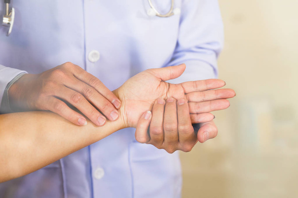 Doctor hands feeling pulse on female wrist - 写真・画像