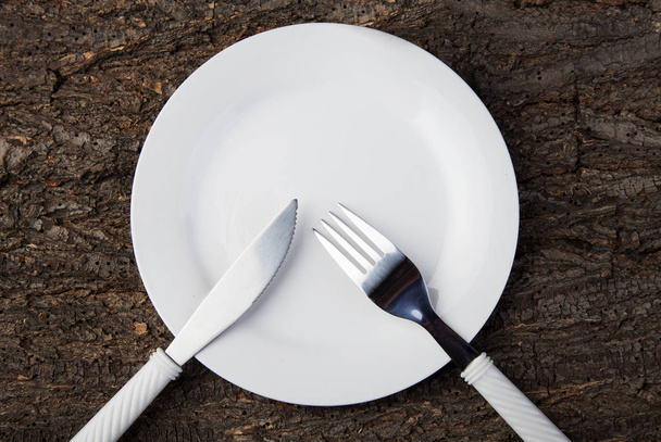 Plate white fork knife empty wooden table closeup photo - Photo, image