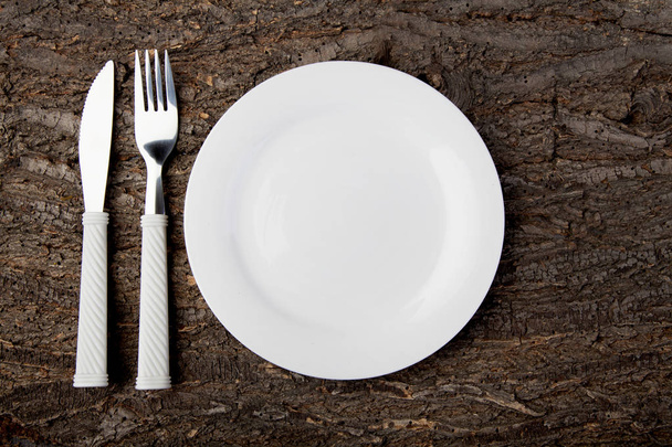 Plate white fork knife empty wooden table top view - Zdjęcie, obraz