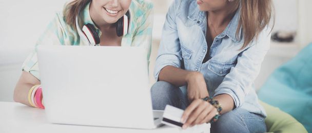 Two young women sitting with laptop and credit cart at home - Foto, Imagen
