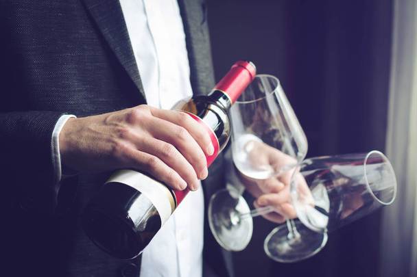 Чоловік наливає червоне вино в склянку
 - Фото, зображення