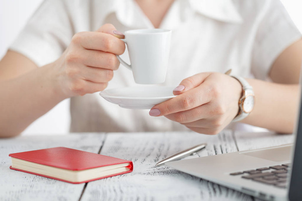 Female designer hands holding cup of hot beverage and working wi - Фото, изображение