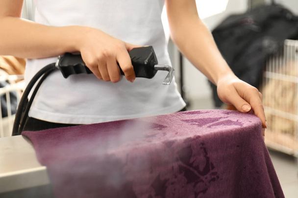 Laundry worker removing stains using special equipment - Φωτογραφία, εικόνα