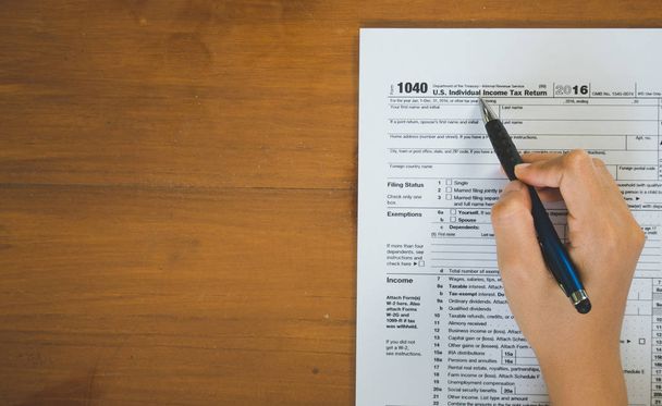 Visão superior da caneta de mão preencher os detalhes sobre os formulários fiscais p
 - Foto, Imagem