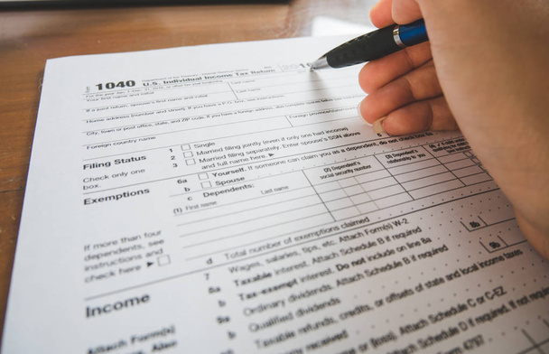 Zakelijke vrouw hand Houd pen vulling in de details op het belastingformulier - Foto, afbeelding