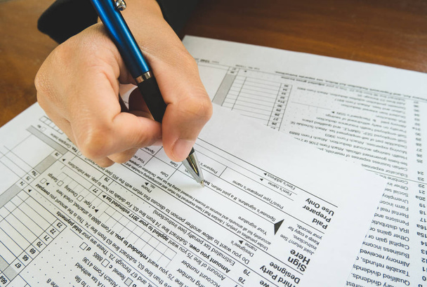 Hand Houd pen op teken punt op het papier van belasting formulieren in business c - Foto, afbeelding