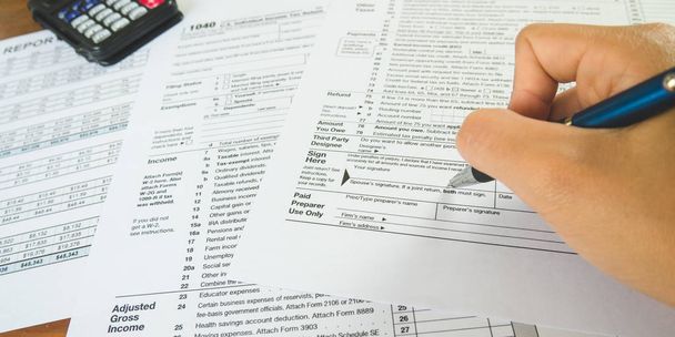 Sostenga la pluma en el punto de la muestra en el papel de los formularios de impuestos en el negocio c
 - Foto, imagen