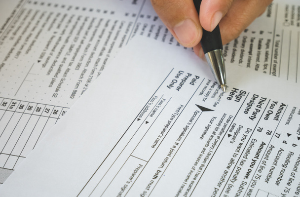 Ручная ручка на знаке на бумаге налоговых форм в бизнесе c
 - Фото, изображение