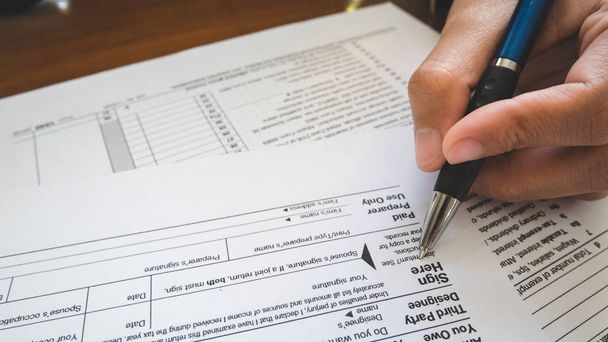 Рука тримає ручку на знаковій точці на папері податкових бланків у бізнесі c
 - Фото, зображення