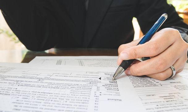 Рука тримає ручку на знаковій точці на папері податкових бланків у бізнесі c
 - Фото, зображення